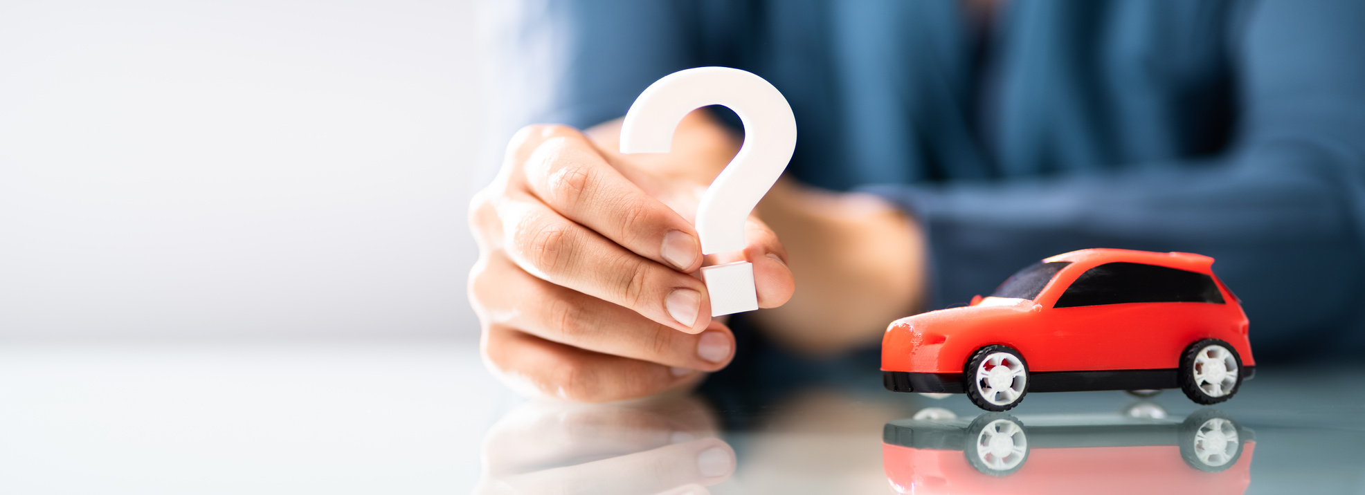 Person Hand Holding Question Mark Next To Car